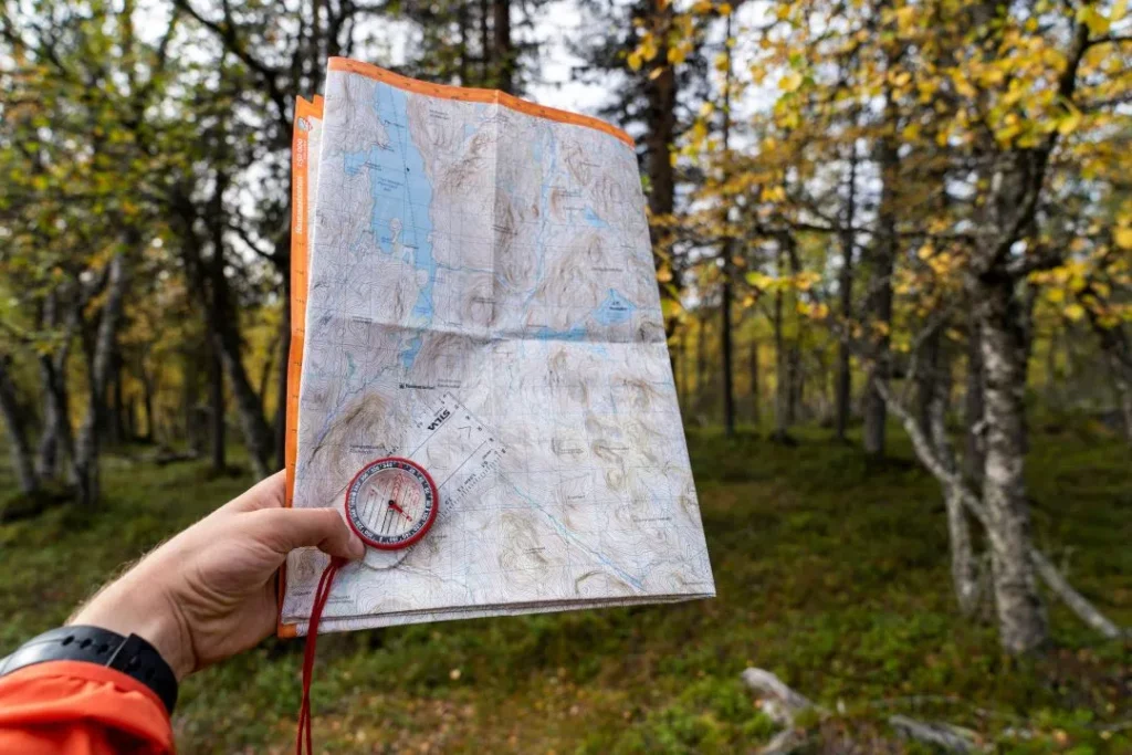 Walker holding a map and compass in a forest