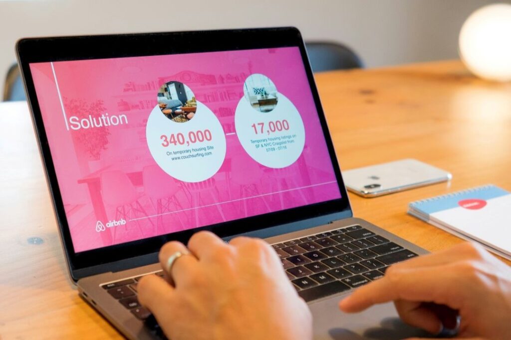 Close up of a person using a black laptop with a PowerPoint presentation showing for Airbnb